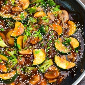 stir fried zucchini and other vegetables in stir fry sauce with sesame seeds and green onion.