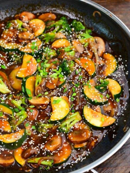 stir fried zucchini and other vegetables in stir fry sauce with sesame seeds and green onion.
