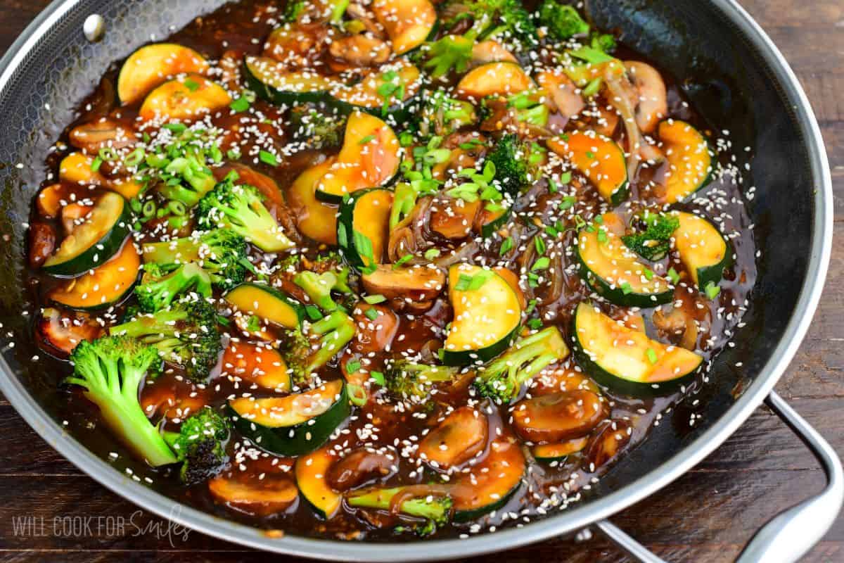Zucchini stir-fry with broccoli, mushrooms, and onions in a savory sauce, garnished with sesame seeds and green onions.