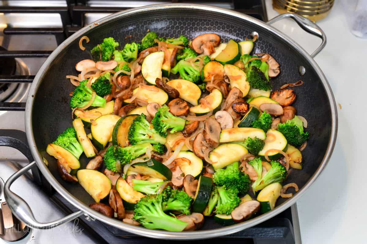 Broccoli, zucchini, mushrooms, and onions sautéing in a large skillet until lightly browned and tender.