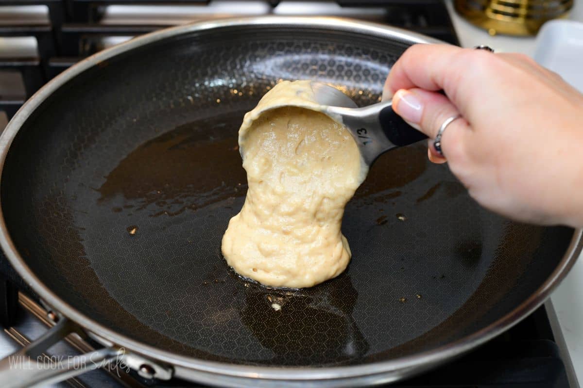 Pouring banana pancake batter onto a lightly greased skillet or griddle over medium heat.