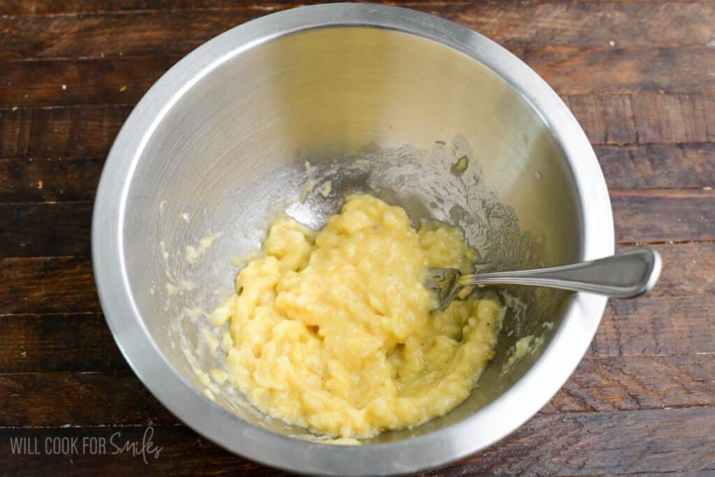 Mashed ripe banana mixed in a bowl with a fork, ready to make banana pancakes.