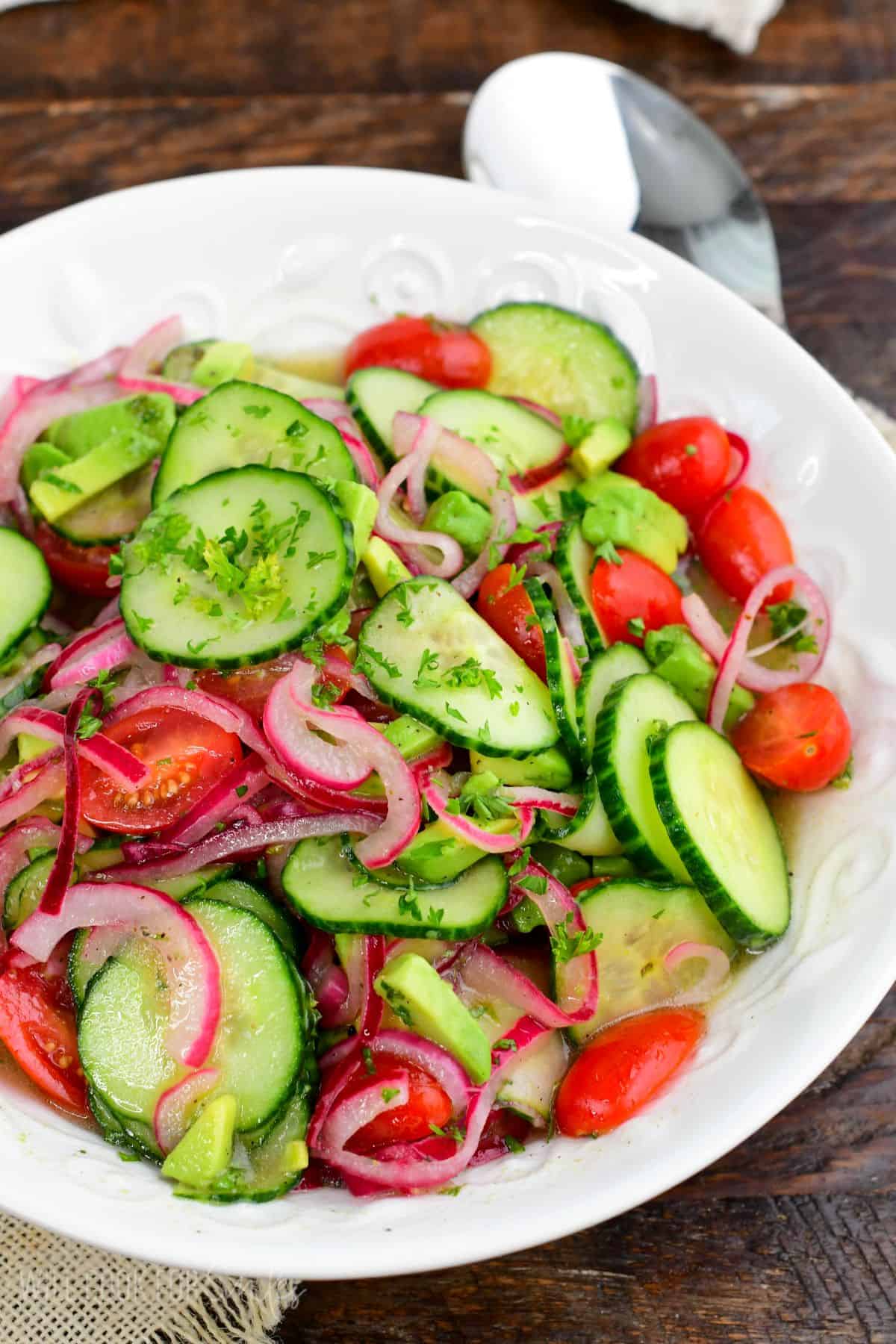 Cucumber tomato onion salad with avocado, grape tomatoes, fresh herbs, and a light vinaigrette.