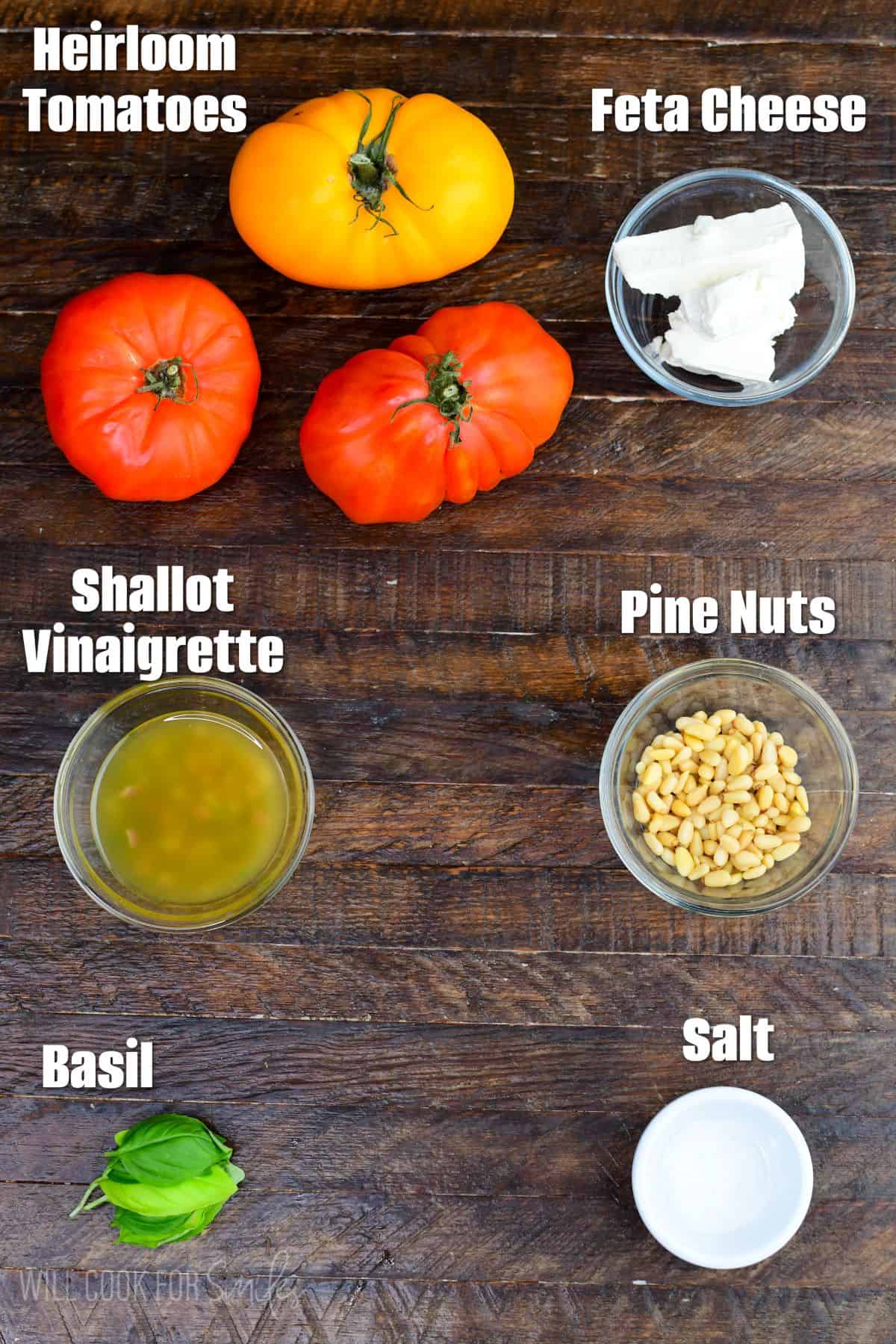 labeled ingredients to make heirloom tomato salad on the wooden background.
