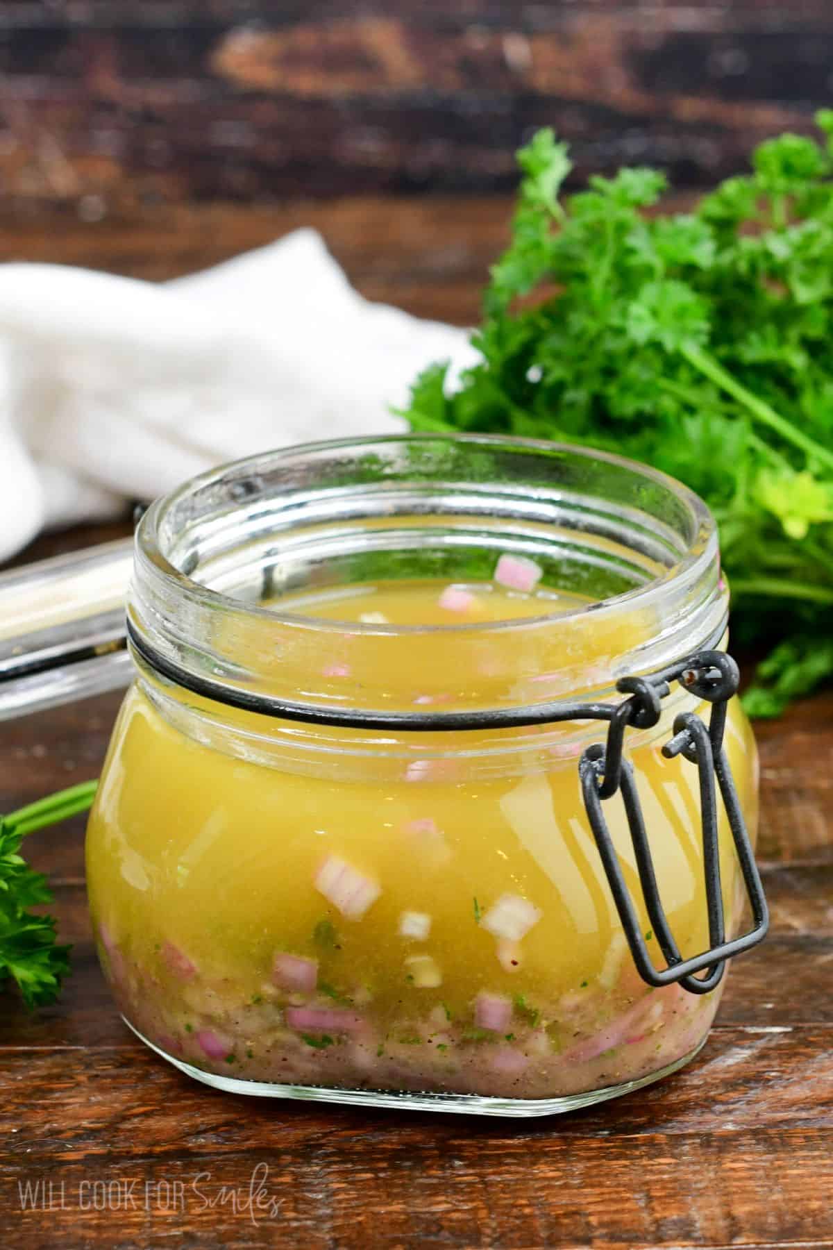 shallot vinaigrette in a glass jar with a lid next to bunch of parsley.