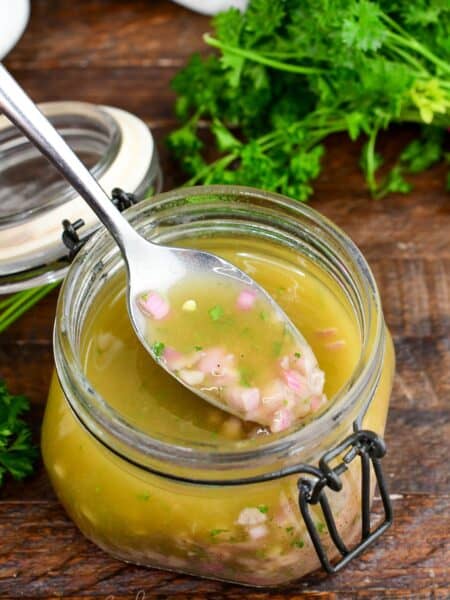 scooping some shallot vinaigrette out of the jar with a spoon.
