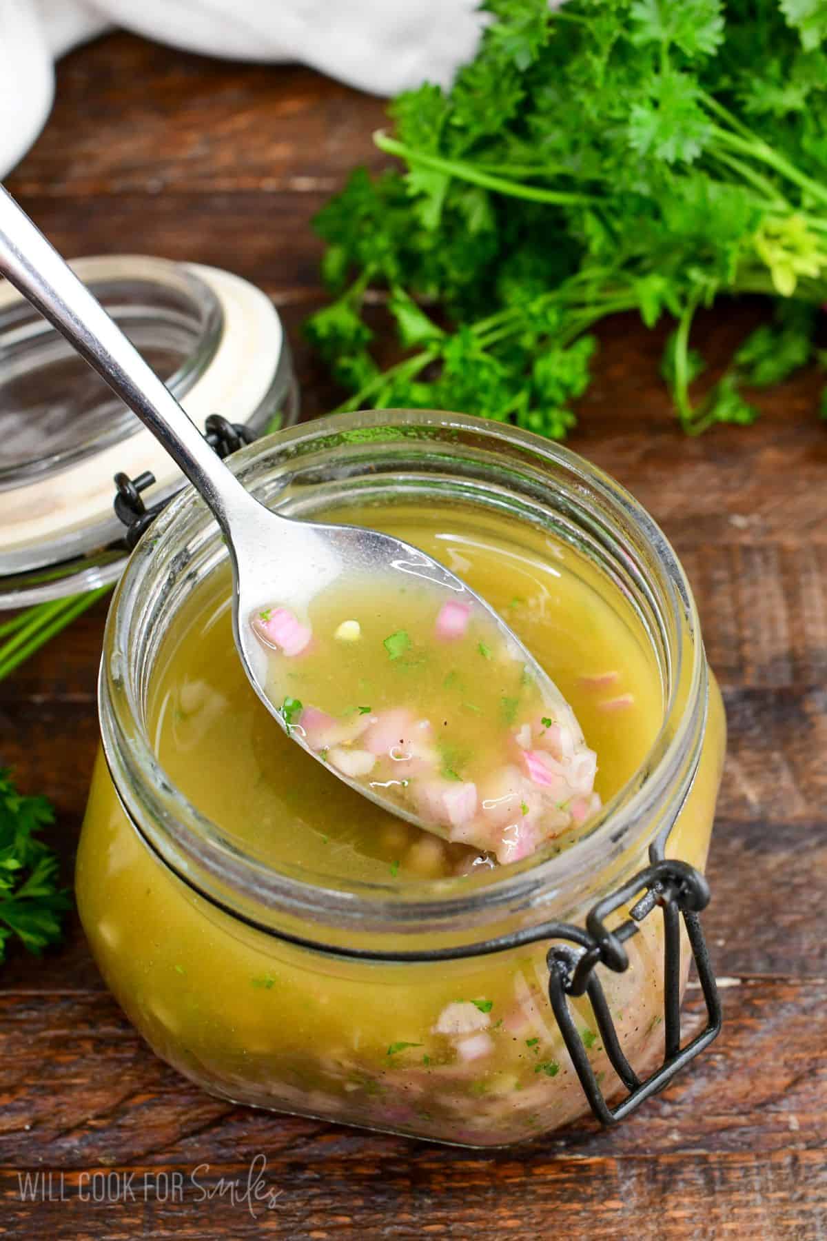 scooping some shallot vinaigrette out of the jar with a spoon.