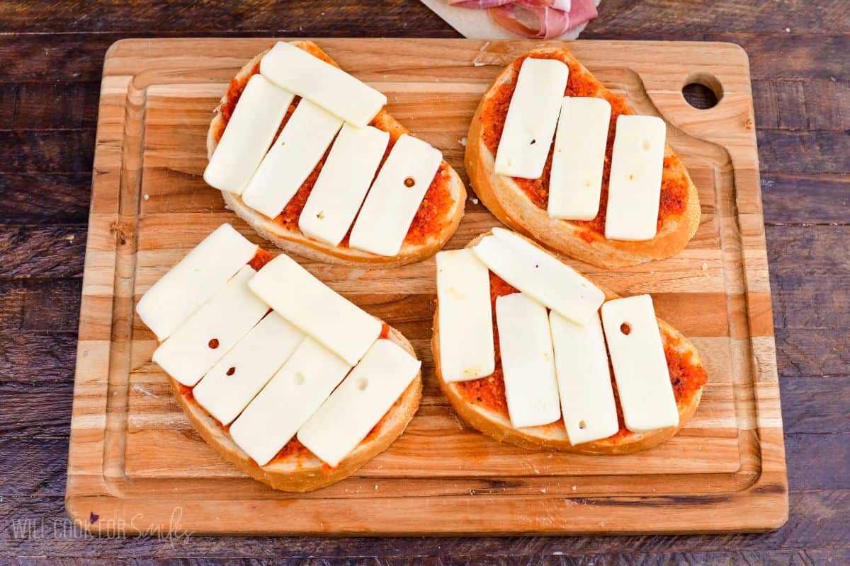 adding fontina cheese over sun dried tomato pesto on the Italian bread slices.