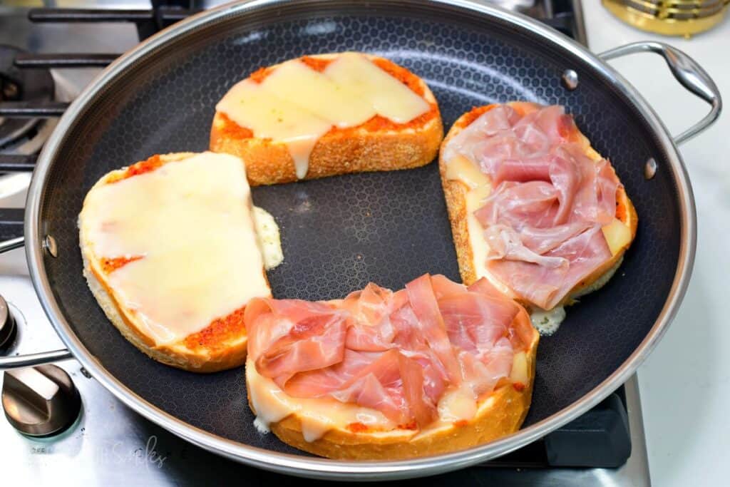 cooking the grilled cheese slices open in the large cooking pan until melted.