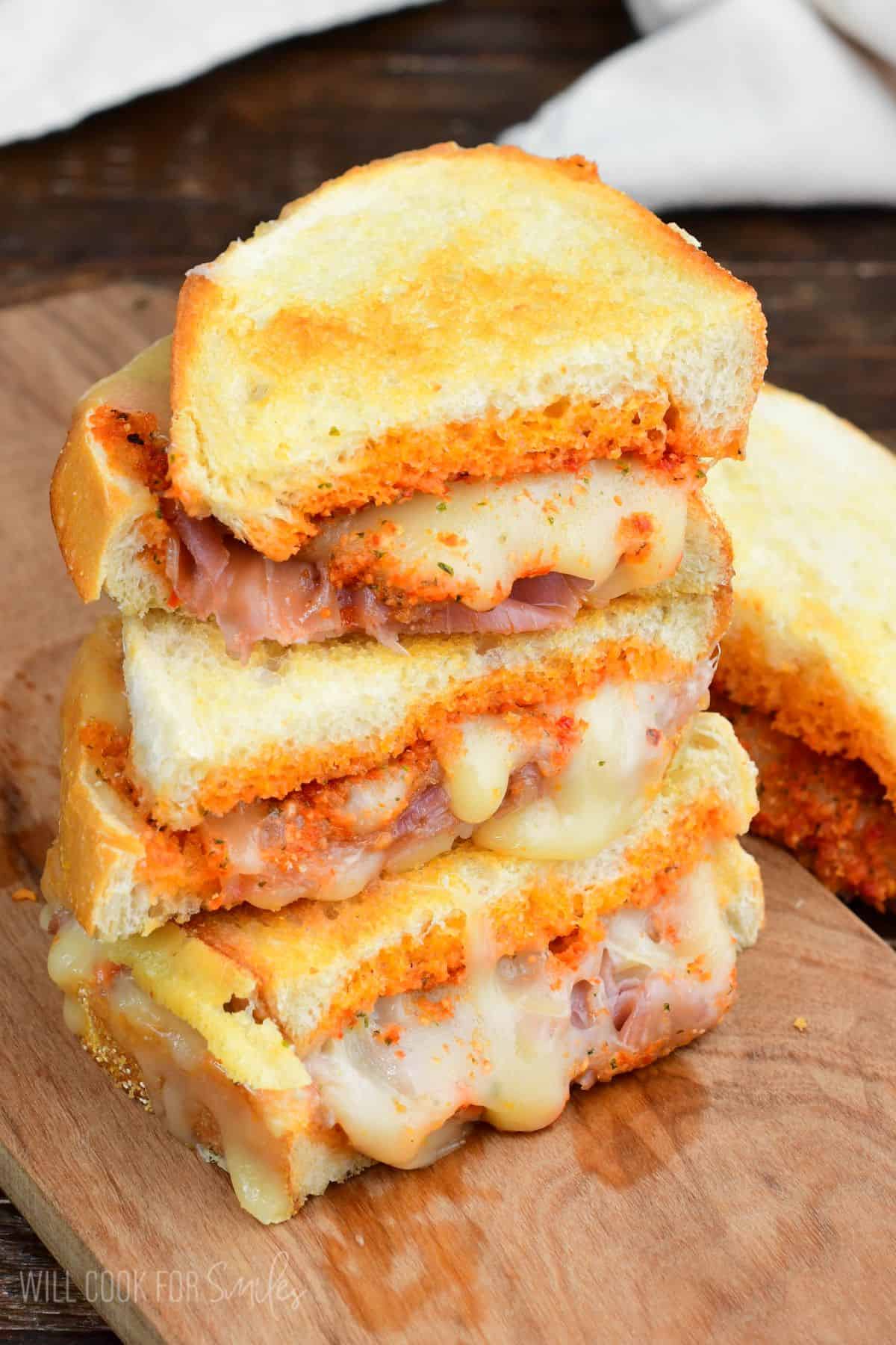 Stacked three halves of a pesto grilled cheese with some cheese oozing out.