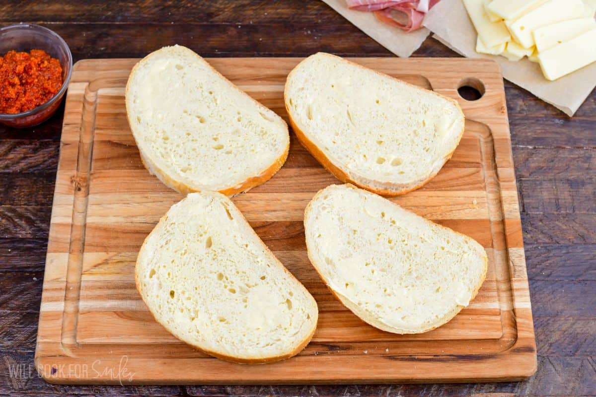 spreading butter onto Italian bread slices to make a grilled cheese.