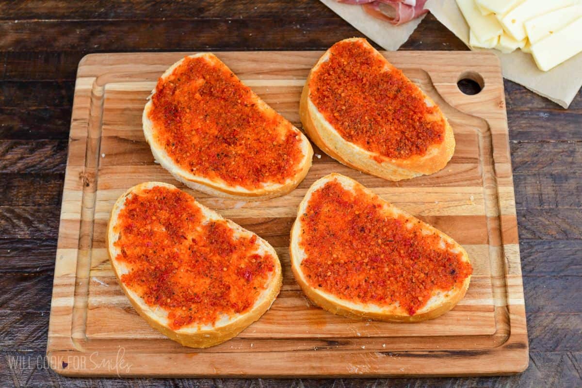 spreading sun dried tomato onto Italian bread slices to make pesto grilled cheese.