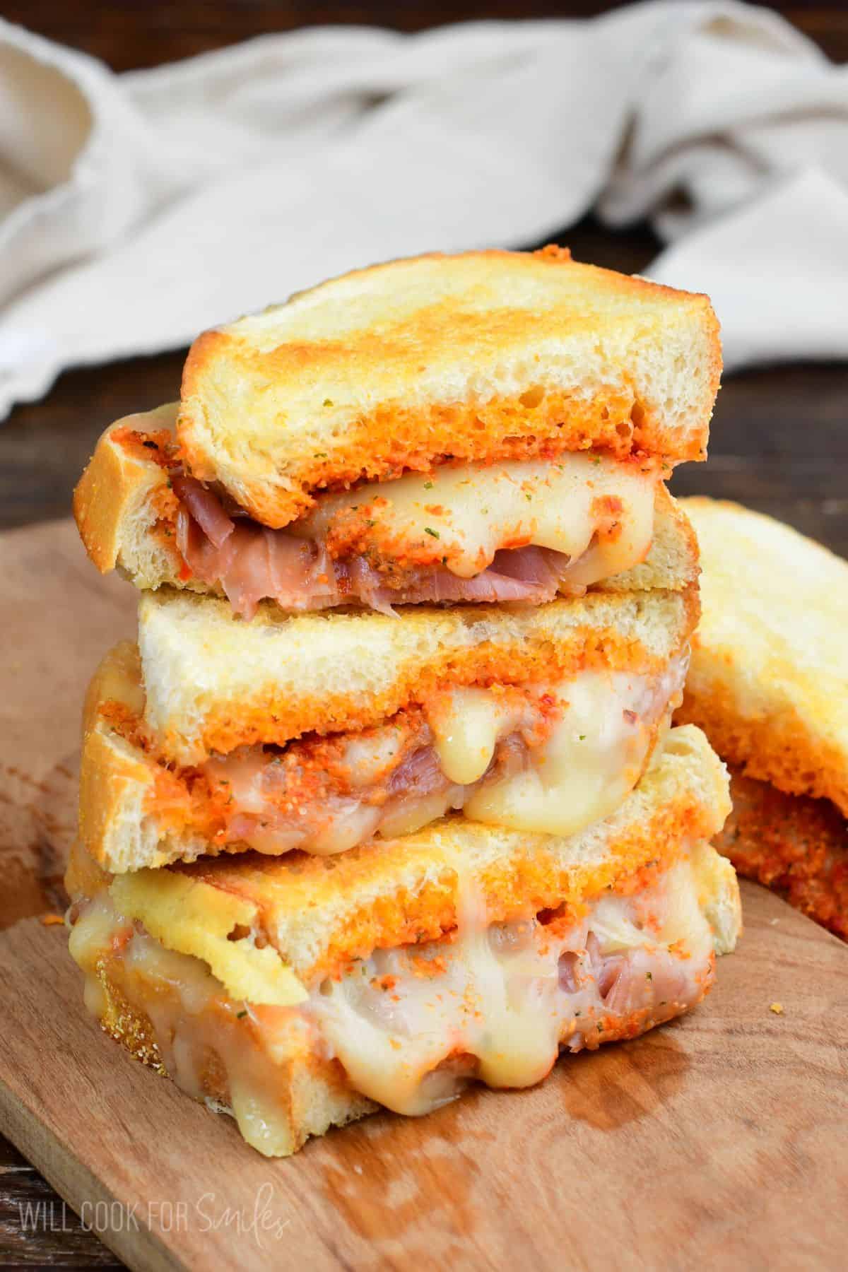Stacked halves of pesto grilled cheese with fontina cheese, sun dried tomato pesto, and prosciutto.