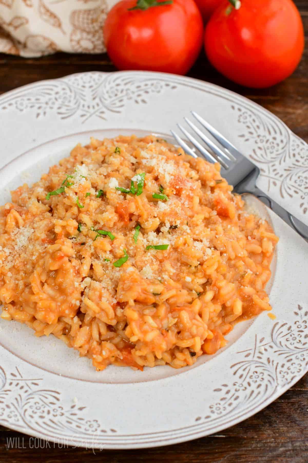 creamy tomato risotto topped with parmesan cheese and basil on the plate.