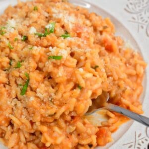 scooping out some creamy tomato risotto from the pate with a fork.