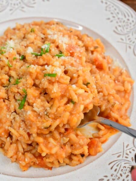 scooping out some creamy tomato risotto from the pate with a fork.