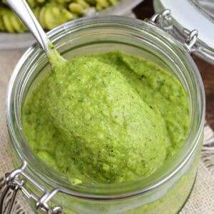 Spoonful of creamy homemade zucchini pesto scooped from a glass jar.