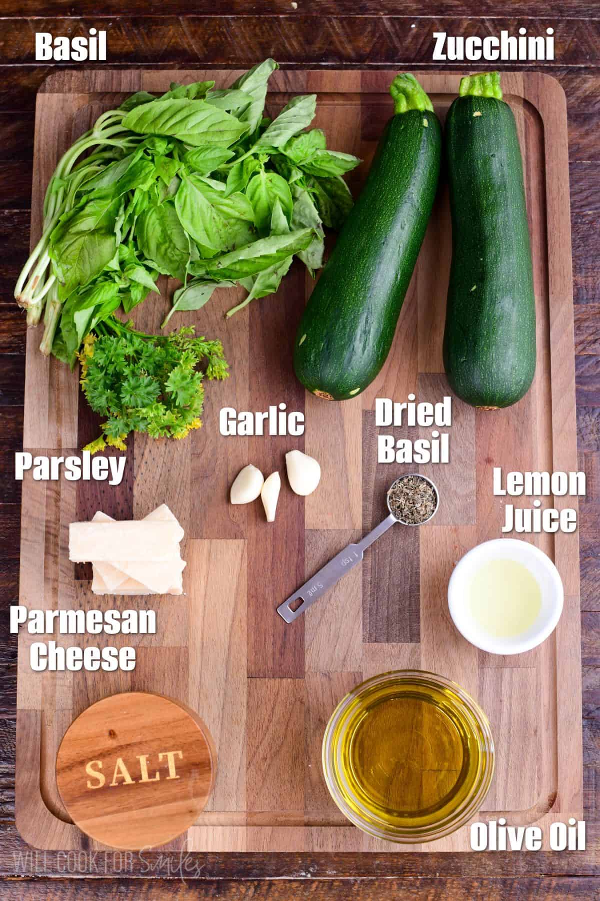 Labeled ingredients for Zucchini Pesto on a wood cutting board.