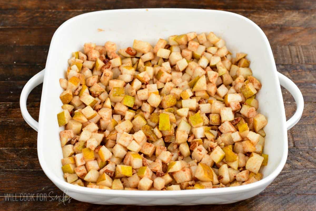 Diced spiced pears spread evenly in a baking dish, ready to be topped and baked into pear crisp.