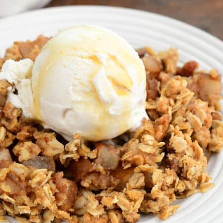 Asian pear crisp with a crunchy oat topping, vanilla ice cream, and maple syrup on a plate.