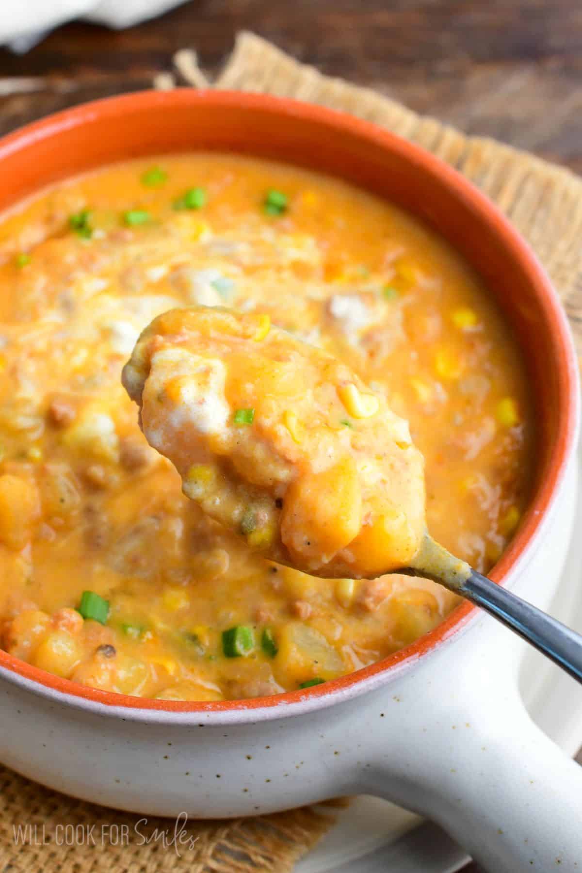 Creamy chorizo potato soup with corn and tender potatoes scooped onto a spoon.