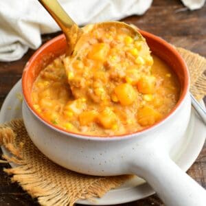 pouring a ladleful of creamy chorizo sausage potato soup into the bowl.