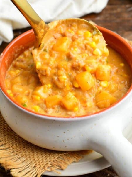 pouring a ladleful of creamy chorizo sausage potato soup into the bowl.