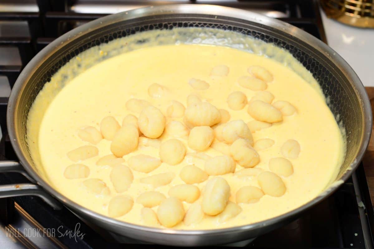 Gnocchi added to a skillet of creamy pumpkin Alfredo sauce.