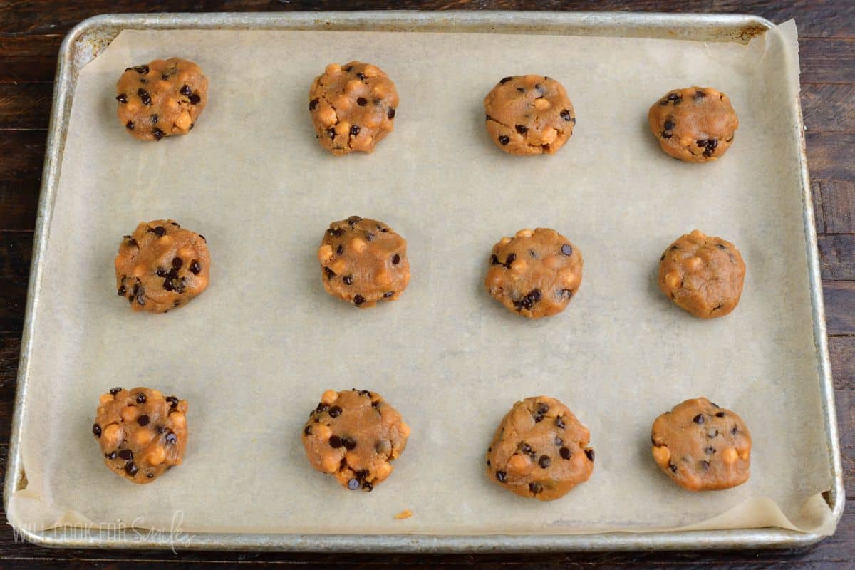 Peanut butter cookie dough topped with chocolate chips and caramel bits in a mixing bowl.