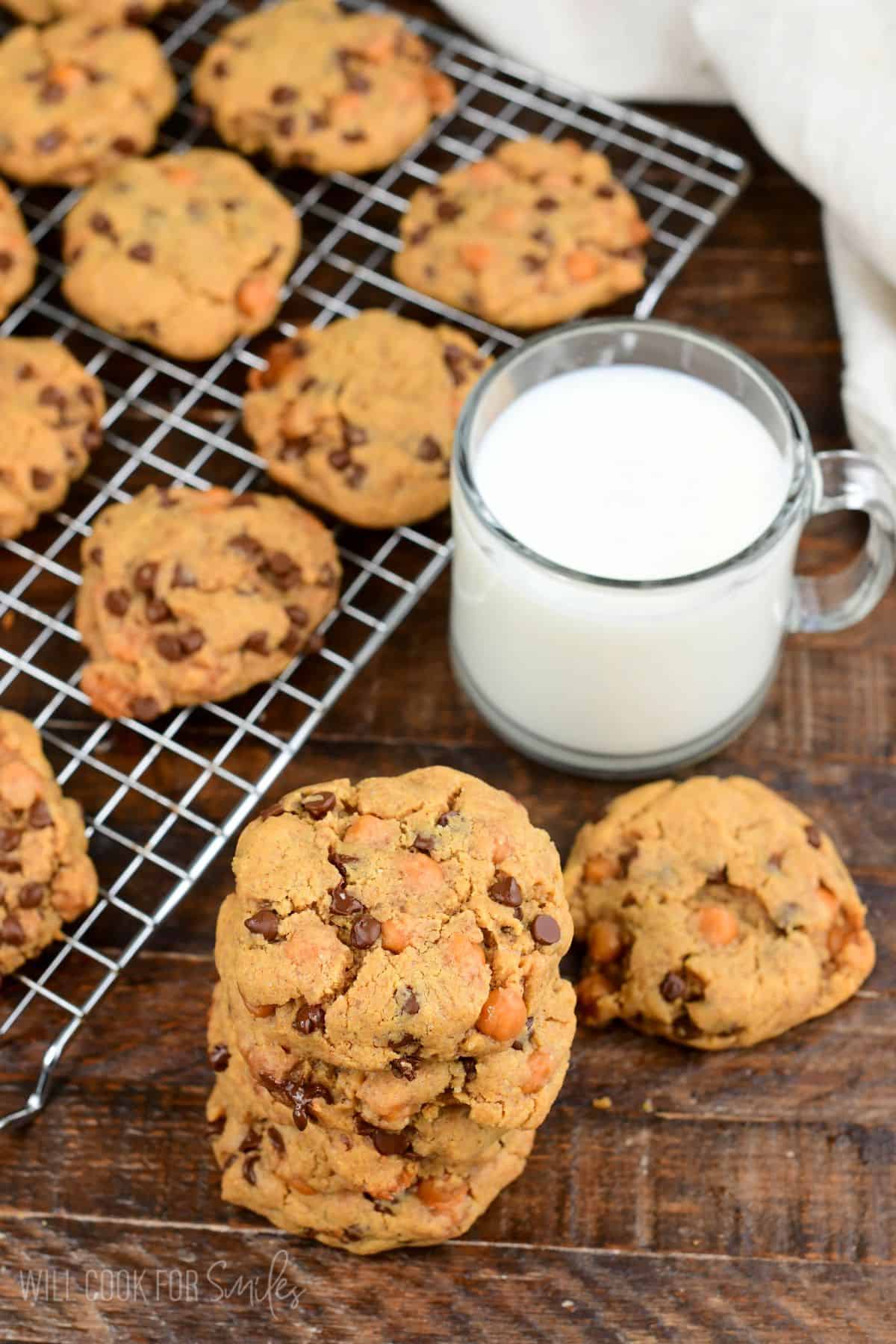 Peanut butter cookies with chocolate chips and caramel bits served with a glass of milk.