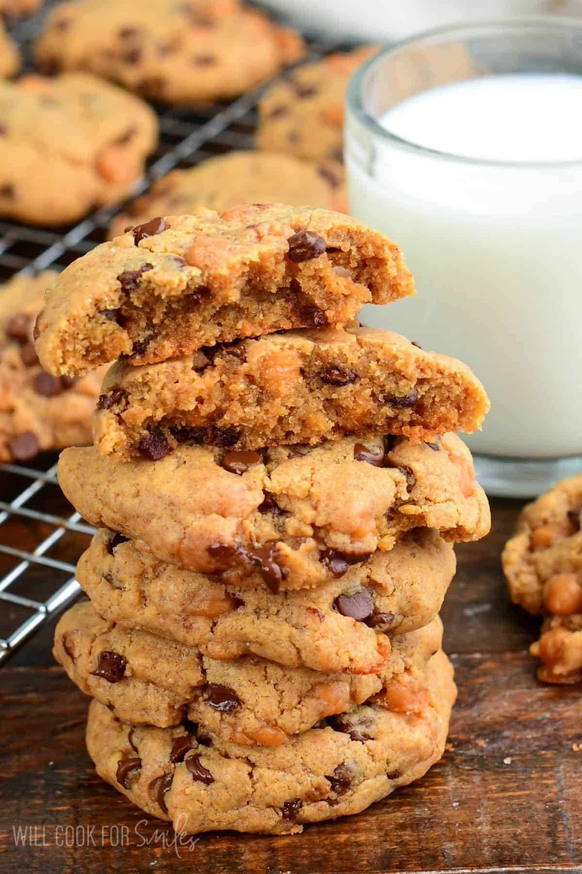 Stack of thick peanut butter cookies with chocolate chips and caramel bits, with one cookie split open on top.