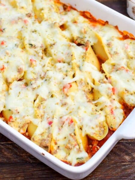 baked Italian sausage stuffed shells in the marinara sauce in a baking dish with melted cheese on top.