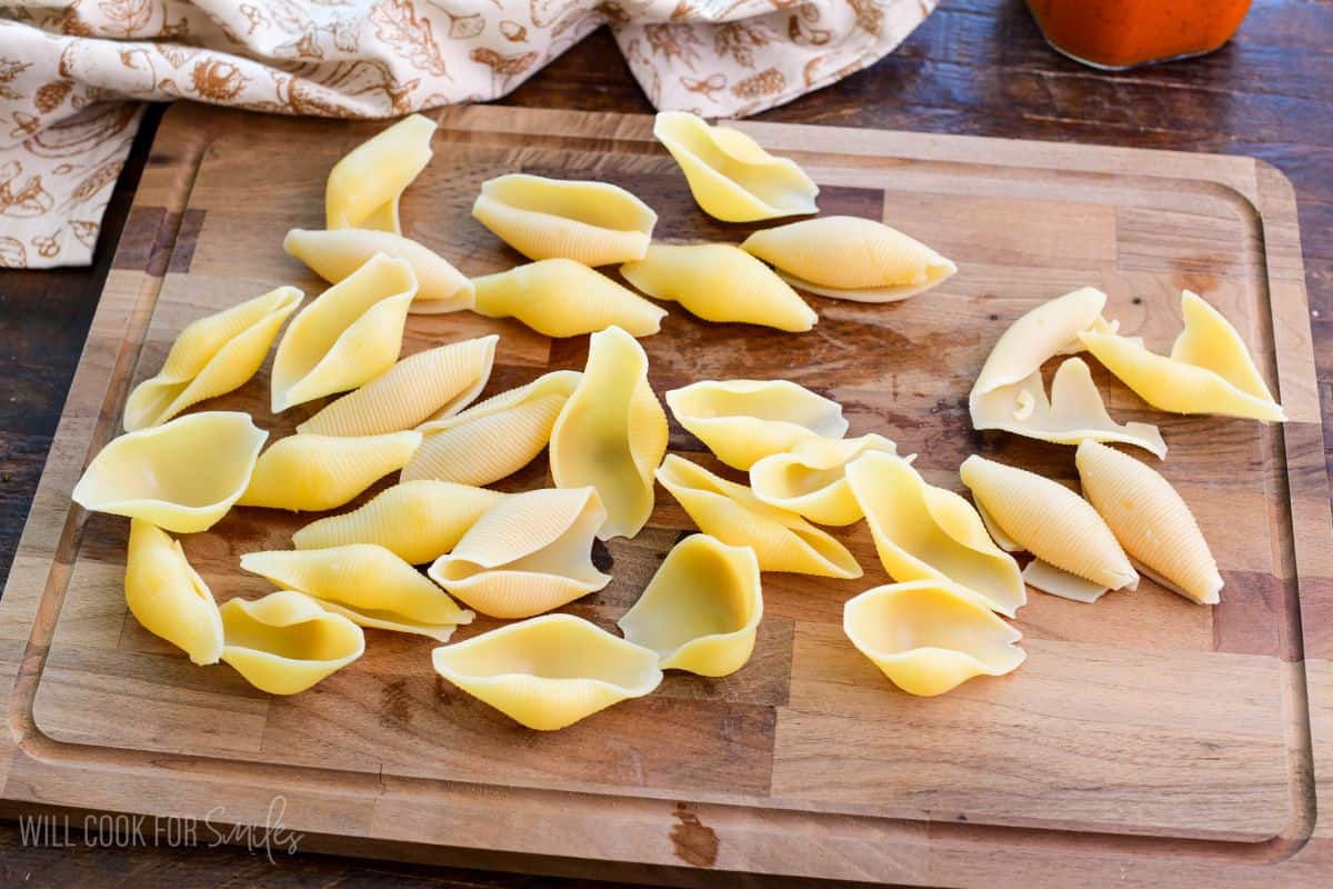 spread out cooked jumbo shells cooling on cutting board.