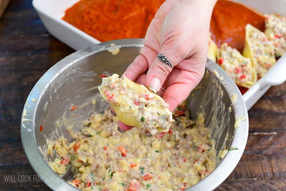 holding a stuffed shell with sausage ricotta filling.