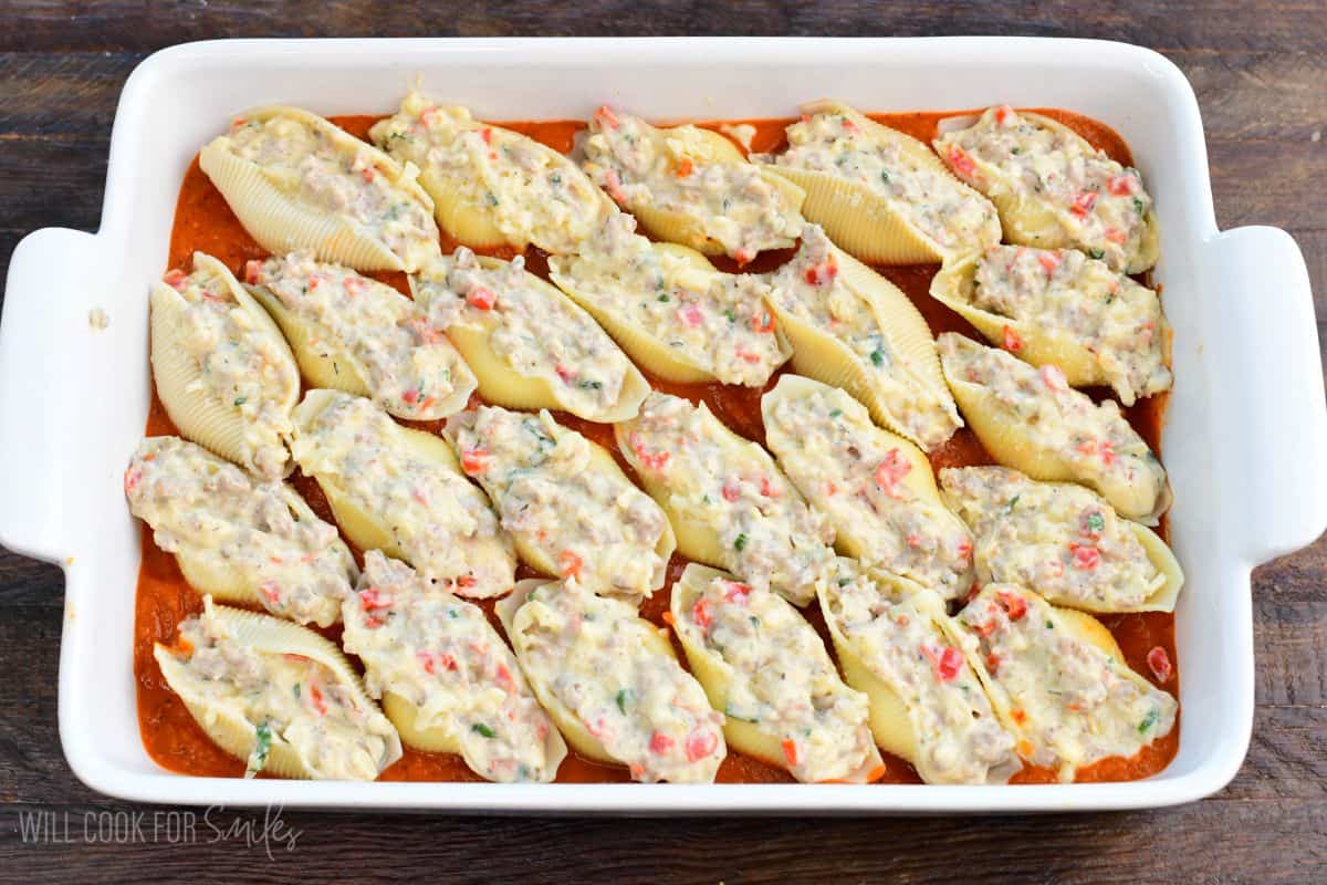 unbaked Italian stuffed sausage shells nestled in the marinara before extra cheese.