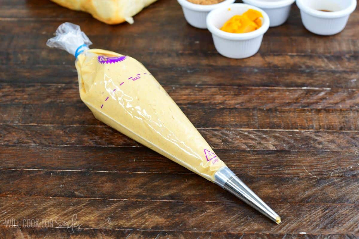 Pumpkin cheesecake filling in a piping bag ready to fill Hawaiian rolls for stuffed French toast.