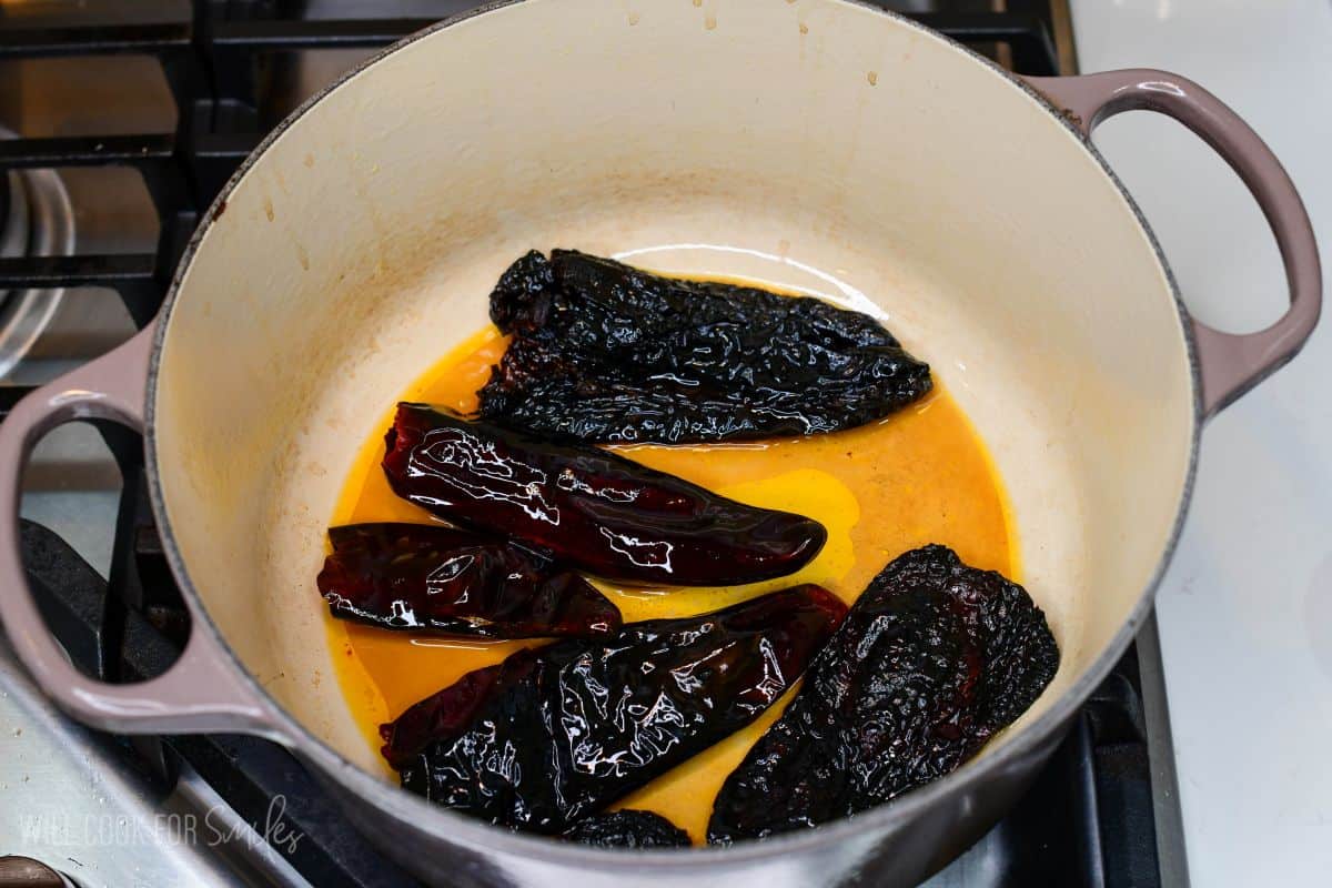 Dried chili peppers rehydrating in a pot for homemade short rib chili.