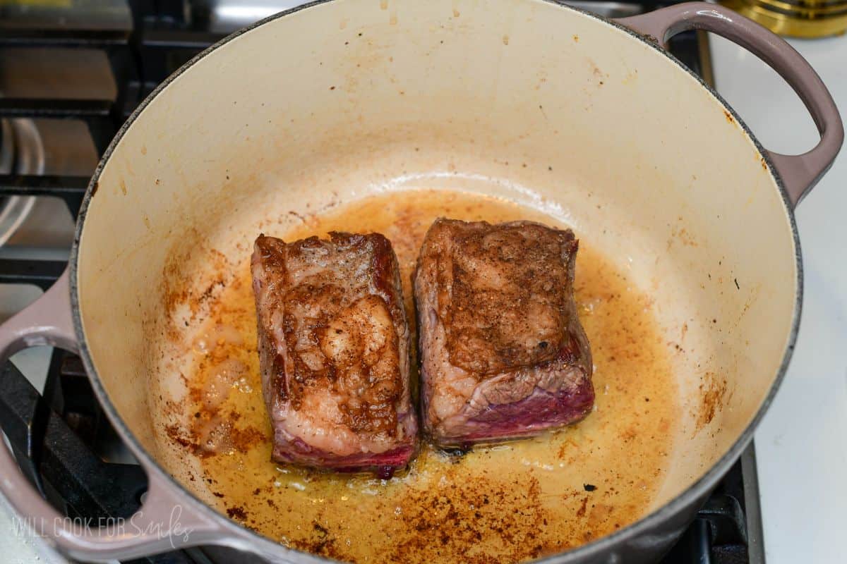 Short ribs searing in a Dutch oven until browned for homemade short rib chili.