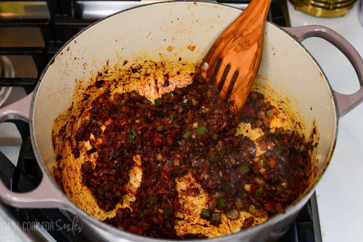 Vegetables, chili paste, and seasonings cooking together in a Dutch oven for short rib chili.